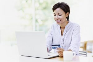 Attractive African American woman using her laptop at home to make online purchases with her credit card