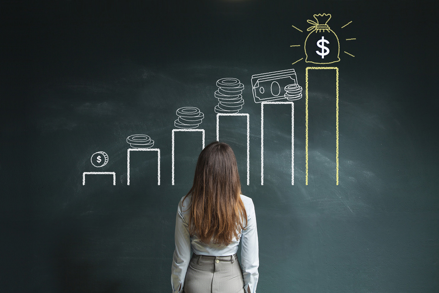 Person standing in front of a chalkboard with a drawn bar chart showing increasing stacks of coins and cash, culminating in a large money bag symbolizing financial growth.